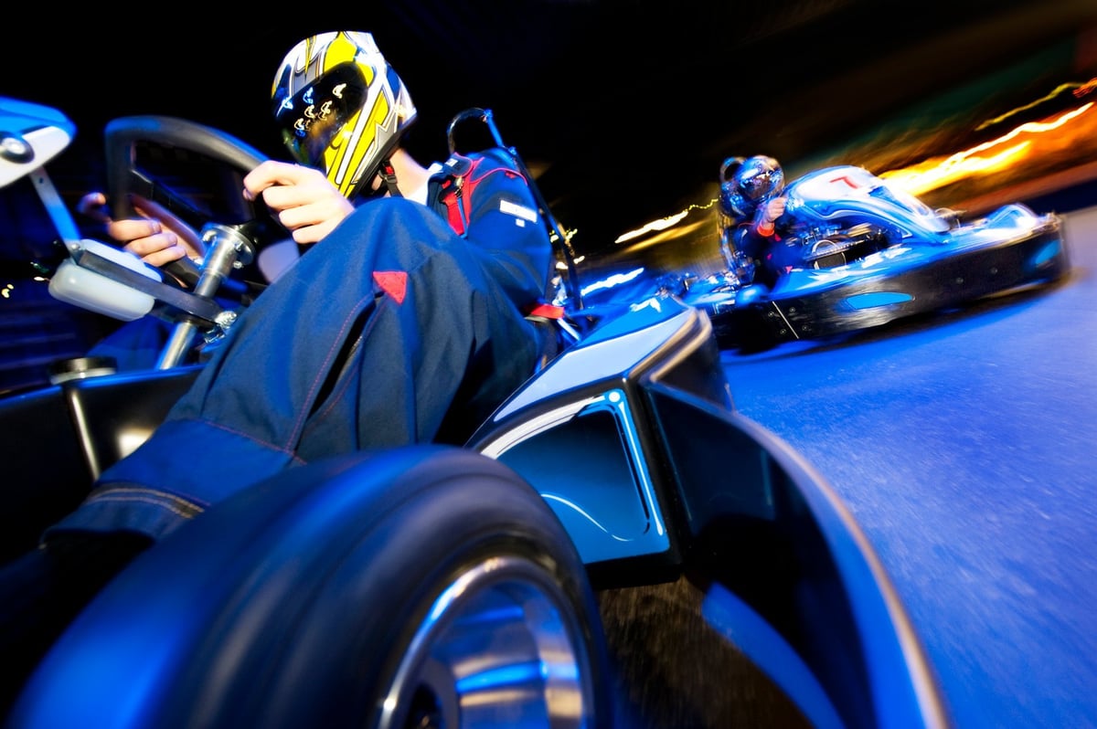 Two karts battling side by side through a corner on the indoor circuit
