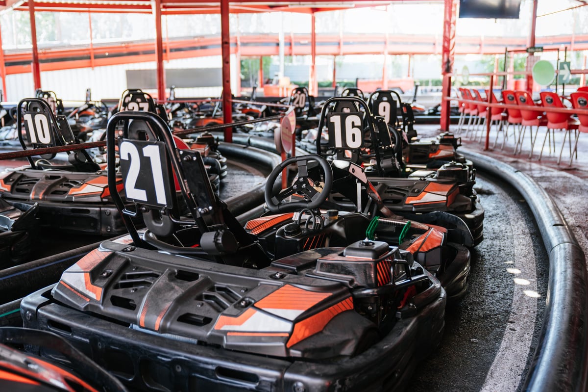 A row of numbered karts lined up on the indoor track waiting for the next race